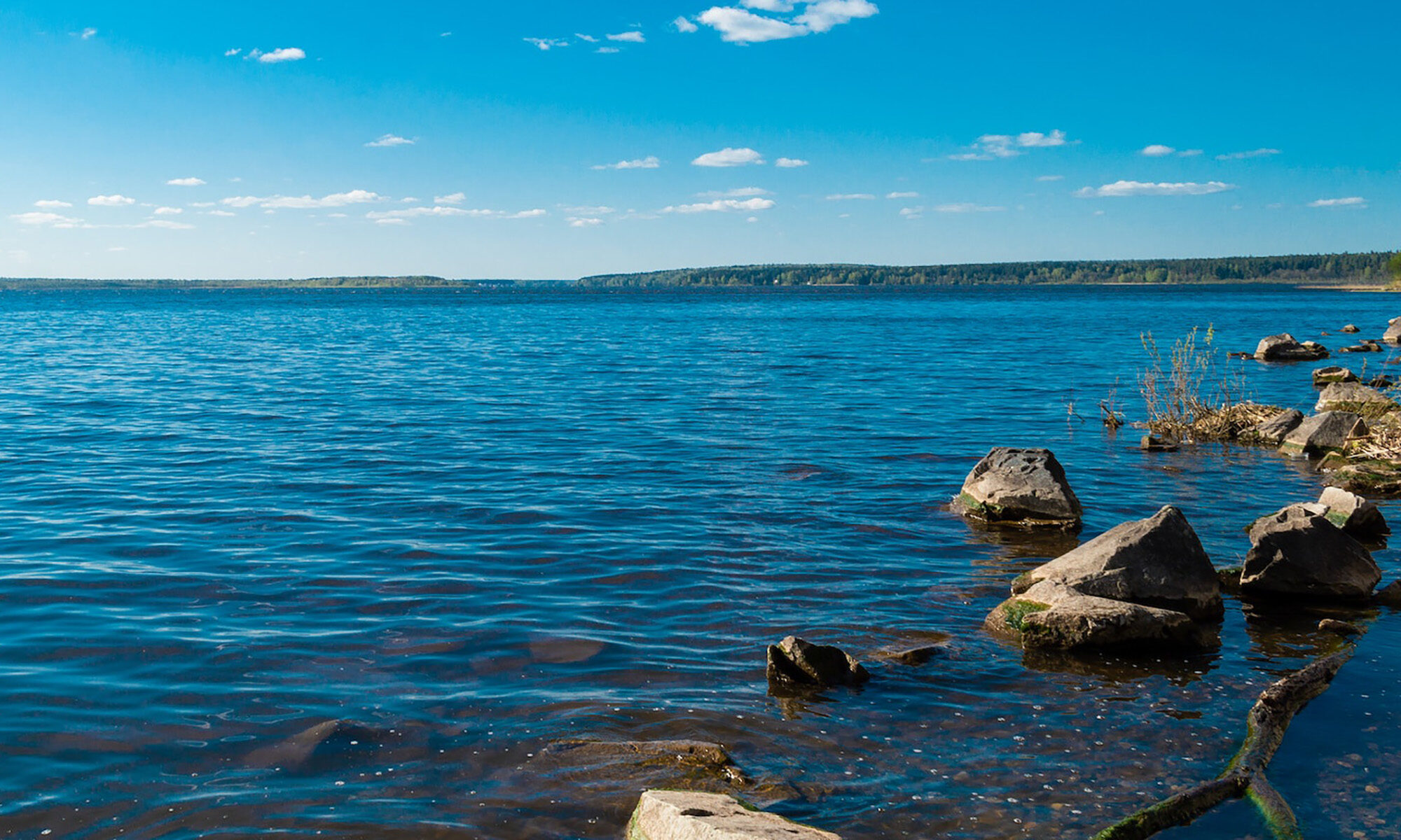 Järvimaisema, etualalla pintaan ulottuvia kiviä.